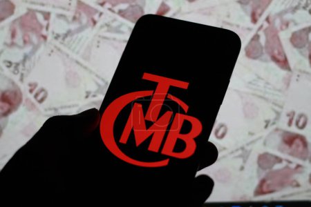 Foto de Indonesia-30 de marzo de 2024: Banco Central de Turkiye, Trkiye Cumhuriyet Merkez Bankas, TCMB, visualizado en la pantalla del teléfono inteligente Con dinero turkiye en segundo plano. - Imagen libre de derechos