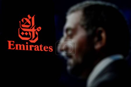 Photo for Indonesia - April 7th 2024: Emirates Airlines logo is displayed on smartphone screen With CEO Ahmed bin Saeed Al Maktoum in background. - Royalty Free Image