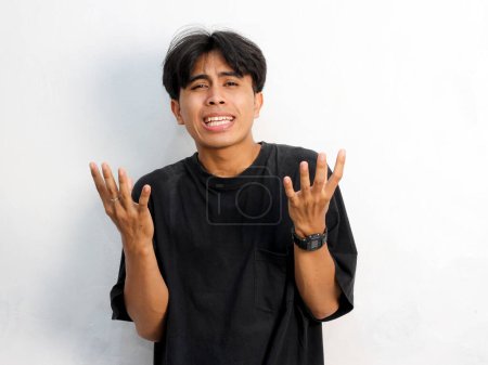 Portrait von lustigem schockiertem Gesicht junger asiatischer Mann mit schwarzem T-Shirt Steht mit ausgebreiteter Hand und reagiert auf etwas Isoliertes auf weißem Hintergrund