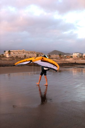 Ein Mann geht mit Flügelblech am Strand des Ozeans entlang. Hochwertiges Foto