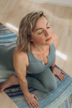 A 50-year-old woman does yoga at home. High quality photo