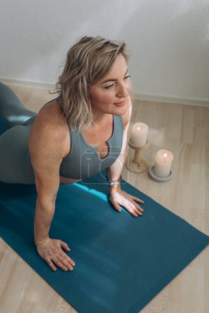 Una mujer de 50 años hace yoga en casa. Foto de alta calidad