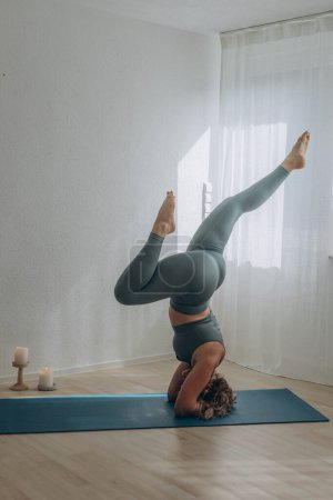 Téléchargez les photos : Une femme de 50 ans fait du yoga à la maison. Photo de haute qualité - en image libre de droit