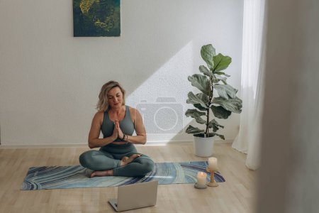 A 50-year-old woman doing online yoga at home. High quality photo