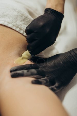 Woman cosmetologist doing sugaring hair removal under armpit. High quality photo