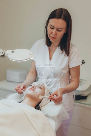 Téléchargez les photos : Cosmetologue esthéticienne effectue un traitement de la peau et de rajeunissement. Photo de haute qualité - en image libre de droit