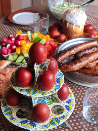 famille célébrant le déjeuner de Pâques avec des ?ufs peints en rouge et cupcake de Pâques et gâteau de Pâques et légumes et saucisses