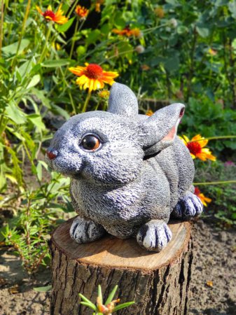 Photo for Garden rabbit figurine on tree stump, greenery, rustic decor, garden decorations, farm - Royalty Free Image