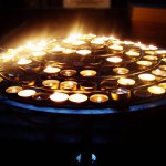 many candles on a pedestal in a church, cathedral. Religion, lanterns, lighting, Christianity, Islam, Ramadan, dark background and light from a candlestick