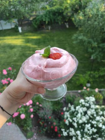 rosafarbenes Dessert mit gemischten Beeren, Erdbeeren, Himbeeren, Minze in einer Glasschüssel, Dessert vor dem Hintergrund der Natur
