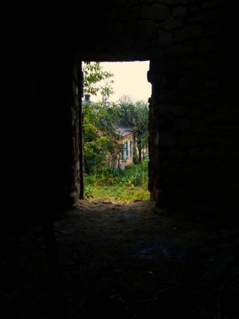 view from the door to a rural house. black background revealing a view of an abandoned hut, village