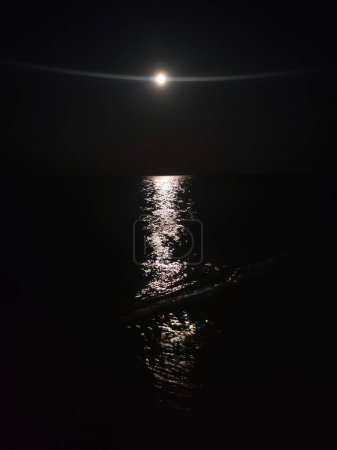 reflet nocturne d'une pleine lune sur la mer, éblouissement de la lune sur l'eau la nuit, le son du surf