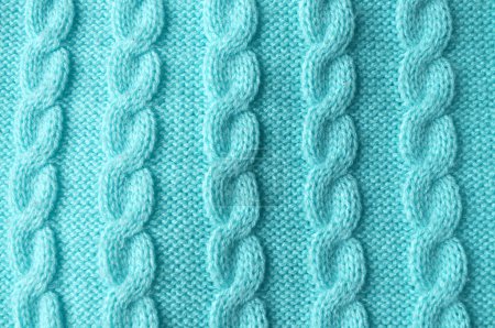 Macro close-up: delicate turquoise knitted fabric with visible stitches resembling a braided pattern. Top view blue, green