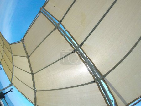 Téléchargez les photos : Toile blanche abstraite, toit sur la plage, auvent protecteur du soleil, voile, ciel bleu - en image libre de droit