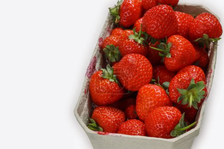 Photo for Freshly harvested ripe garden strawberries in recycled paper food container on a white background, top view close-up. Copy space. - Royalty Free Image