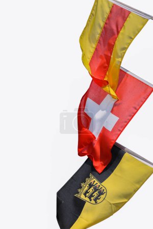 Tres banderas en los asta de la bandera ondeando en el viento. Banderas de Baden, Suiza, Bandera Baden-Wuerttemberg con emblema. Bandera suiza en el medio. Copiar espacio. Aislado sobre fondo blanco. Ruta de recorte