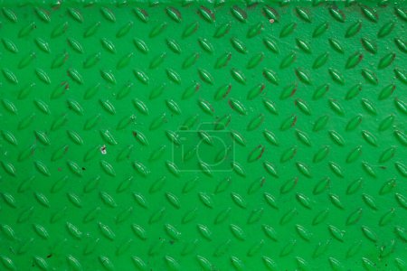Grunge steel industrial boat floor plate painted vivid green anti-rust paint. Rhombus shapes pattern. Robust ferry ship floor metal pattern. Modern design concept. Factory style. Abstract background.