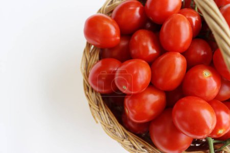 Photo for Many red cherry tomatoes with sepals in the basket isolated on the white background.  Tomato pile. Ripe and fresh organic vegetables harvested from local farmers. Clipping path. Top view. Copy space. - Royalty Free Image
