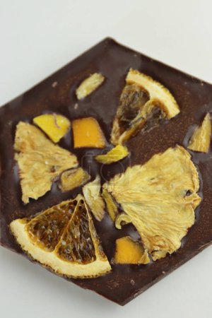 Photo for Handmade dark chocolate bar with a dried fruit topping - slices of orange, mango, pineapple. Homemade Chocolate bark in shape of honeycomb. Top view. Isolated on white background. Copy space - Royalty Free Image