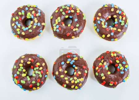 Photo for Set of six tasty chocolate donuts with smarties on white background. 6 Doughnut decorated with colorful nibble on top. Birthday party.  Hanukkah celebration concept. Isolated. Top view - Royalty Free Image