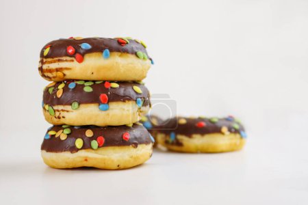 Photo for A stack of doughnuts glazed with chocolate and colorful smarties. Pile of 5 donuts isolated on a white background. Side view. Copy space - Royalty Free Image