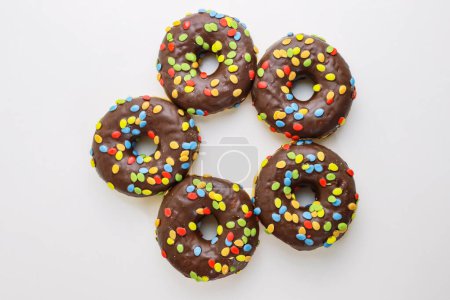 Photo for A set of doughnuts glazed with chocolate and colorful smarties. Five donuts isolated on a white background. Side view. Copy space - Royalty Free Image