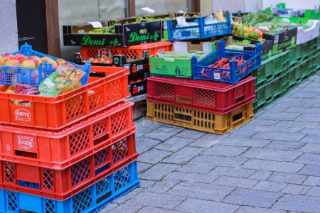 Photo for Ochsenfurt, Germany - April, 27th, 2023: Street food market in old German village in Lower Franconia. Red, blue, green plastic and carton boxes with fresh fruits and vegetables. Selective focus - Royalty Free Image