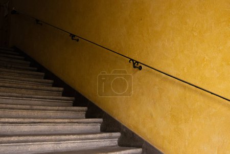 Gelbe Wand mit Treppe und Metallgeländer. Vintage-Hintergrund. Minimalistisches Design und Einfachheit. Basisbild für Poster, Banner oder Cover. Grafische Künste