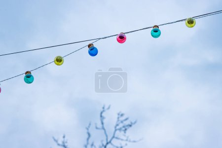 Photo for Christmas garland light bulbs on cloudy sky background. Wedding ceremony decoration. Tree branches without leaves. Backdrop, wallpaper. Minimalistic conceptual simple graphic design idea. Copy space - Royalty Free Image