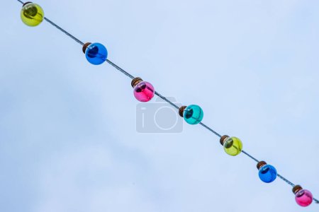 Photo for Christmas garland light bulbs on blue and cloudy sky background. Wedding ceremony decoration. Backdrop, wallpaper idea. Minimalistic conceptual simple graphic design idea for ads, posters. Copy space - Royalty Free Image
