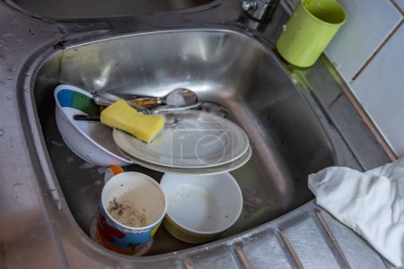 Geschirr reinigen. Schmutzige Tassen, Teller, Messer, Gabeln und Löffel werden in der Spüle der Campingküche gewaschen. Waschutensilien. Metallarbeitsoberfläche der Theke. Ansicht von oben. Selektiver Fokus