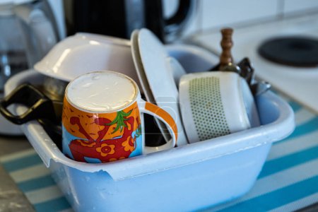 Sauberes Geschirr - Tassen, Teller, Schüsseln, Kochtöpfe trocknen in der kaputten blauen Spülschale in der Campingküche. Trockengeräte auf dem Küchentisch. Selektiver Fokus