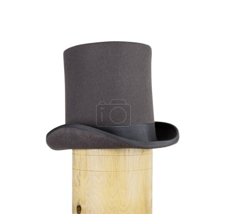 Photo for Magic hat. Topper. Elegant vintage gray beige wool felt top hat with black band on the wooden hat block. Grosgrain ribbon trim around rolled brim. Isolated on white background. Close-up. Copy space. - Royalty Free Image