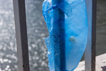 Foto de Bolsa de plástico azul colgada en la barandilla del puente Elisabeth sobre el río Donau en Budapest. Basura en la ciudad. Concepto de contaminación ambiental. Desastre ecológico, catástrofe. Enfoque selectivo - Imagen libre de derechos