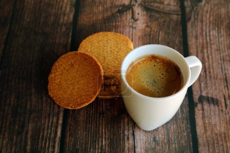 A cup of hot espresso with biscuits on wooden table. Hot coffee with cookies.