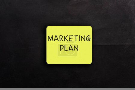 Photo for Yellow card with phrase Marketing Plan on black background upper view. Business strategy to engage customers. Corporate management - Royalty Free Image