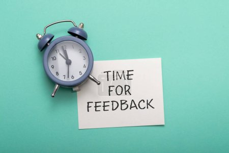 Photo for Blue alarm clock lies on a blue background next to a card with the text time for feedback. Conceptual business photo on the topic of product evaluation and customer reviews. - Royalty Free Image