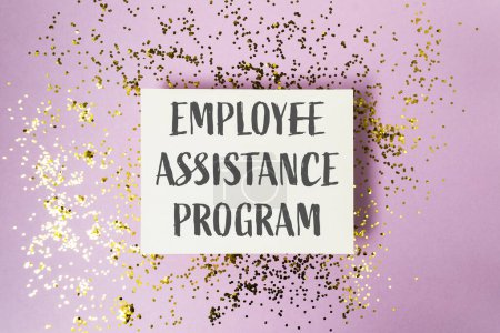 A white sign with gold glitter on it that says Employee Assistance Program. The sign is on top of a purple background