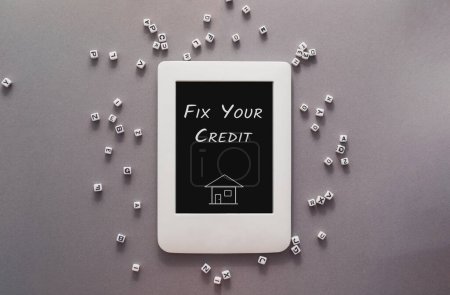 Une tablette blanche avec les mots Fix Your Credit écrit dessus. La tablette est entourée d'une pile de blocs blancs