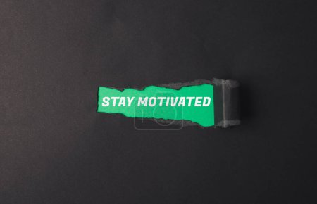 Ein grünes Schild mit der Aufschrift "Bleiben Sie motiviert". Es ist in zwei Hälften gerissen. Das Schild steht auf schwarzem Hintergrund