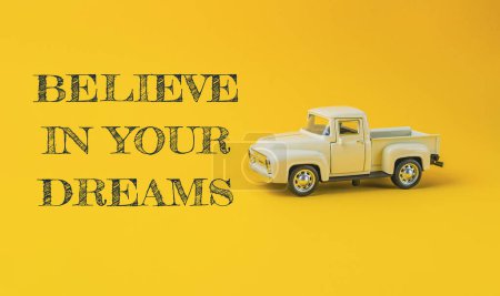 Téléchargez les photos : Un camion jouet est sur un fond jaune avec les mots croire en vos rêves écrits ci-dessous - en image libre de droit