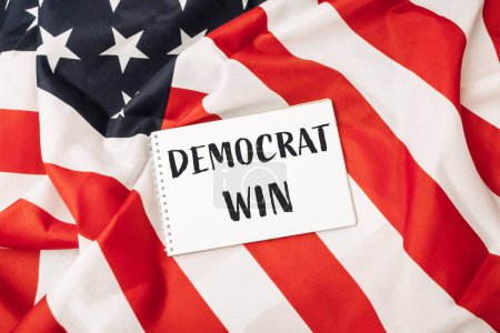 Una bandera americana roja y blanca con un pedazo de papel blanco que dice que los demócratas ganan