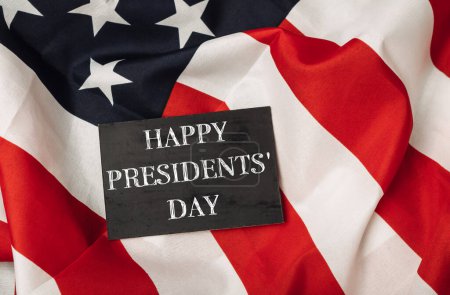 Photo for A black sign with the words Happy Presidents' Day written on it is placed on top of a red and white American flag - Royalty Free Image