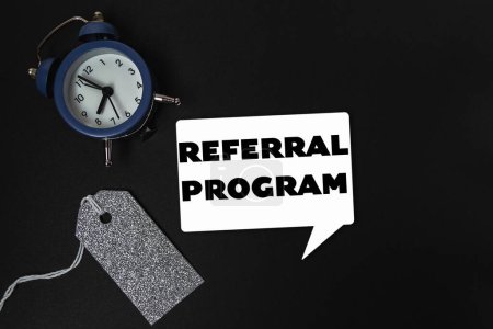A clock is on a table with a tag that says referral program. The clock is blue and white
