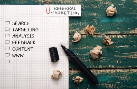 A piece of paper with a marker on it with the words referral marketing written in red