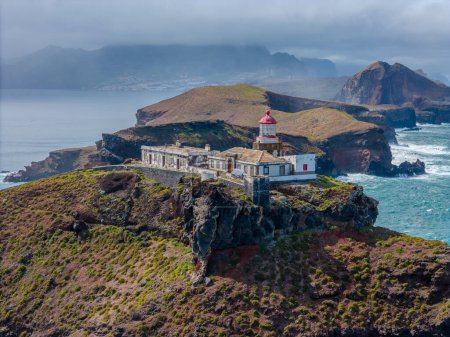 Foto de Faro desde vista aérea en la península de Sao Lourenco en Madeira. Farol da Ponta de So Loureno, Madeira. Faro en una pequeña isla junto al océano con olas, nubes. - Imagen libre de derechos