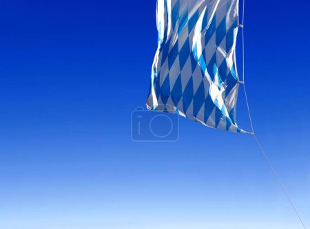 die blau-weißen Diamanten der bayerischen Fahne, die im Wind am blauen Himmel wehen