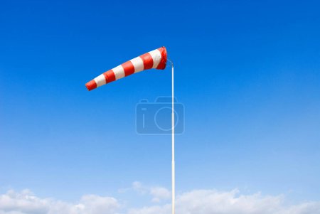 wind sock, wind drogue or wind sleeve, in blue sky, red and white indicating moderate wind