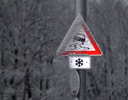 a german traffic sign caution danger of skidding in winter, illuminated by the camera flash
