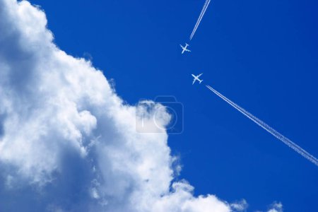deux avions de passagers avec des traînées sur une trajectoire de collision dans le ciel bleu avec des nuages